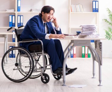 Ofiste çalışan tekerlekli sandalyedeki genç adam.