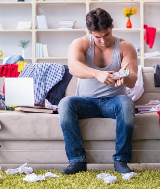 Dağınık odada çalışan genç adam.