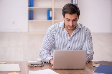 Genç işadamı işyerinde oturuyor.