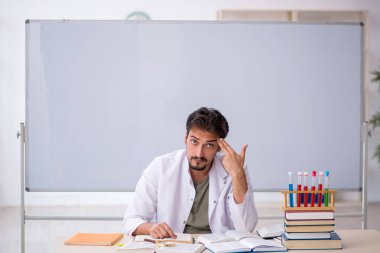 Genç kimyacı öğretmen beyaz tahtanın önünde.