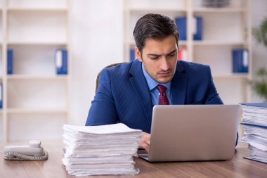 Genç işadamı ve işyerinde çok fazla iş var.