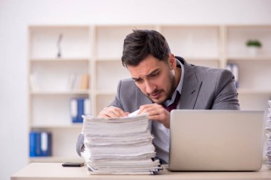 Young employee and too much work at workplace