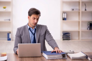 Genç işadamı işyerinde oturuyor.