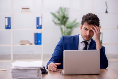 Young employee and too much work at workplace