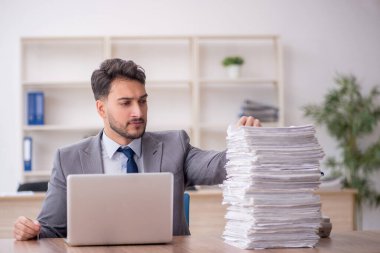 Young employee and too much work at workplace