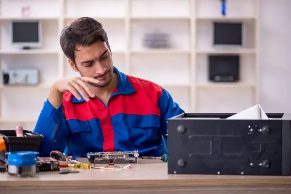 Young repairman repairing computer at workshop