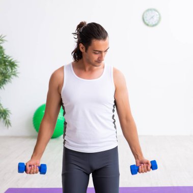 Genç yakışıklı adam içeride spor egzersizleri yapıyor.