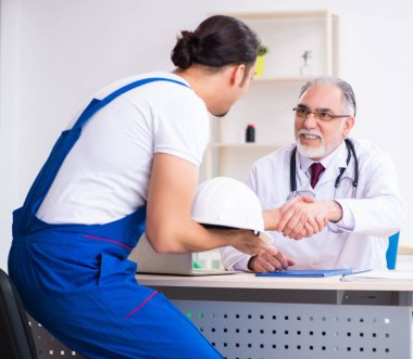 Genç erkek müteahhit yaşlı doktoru ziyaret ediyor.