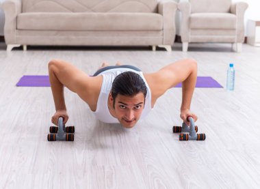 Genç adam evde antrenman ve egzersiz yapıyor.