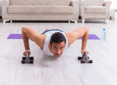 Genç adam evde antrenman ve egzersiz yapıyor.