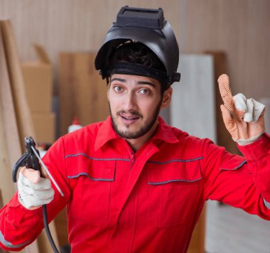 Kaynak tabancası elektrodu ve kaynak metali olan genç bir tamirci.