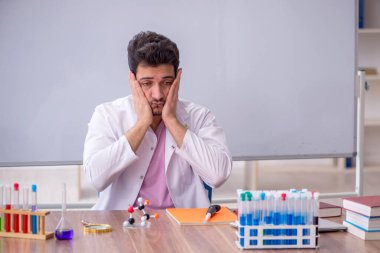 Young chemistry teacher sitting in the classroom