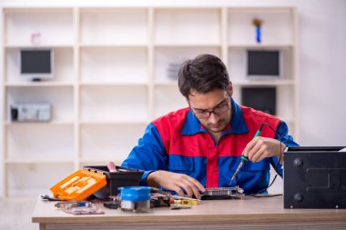 Atölyede bilgisayar tamir eden genç bir tamirci.