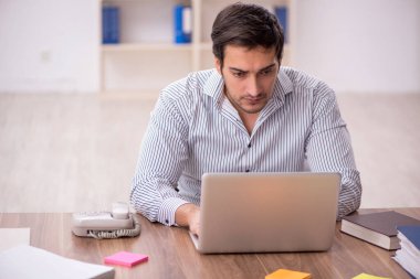 Genç işadamı işyerinde oturuyor.