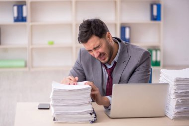 Young employee and too much work at workplace