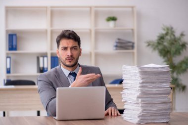 Young employee and too much work at workplace