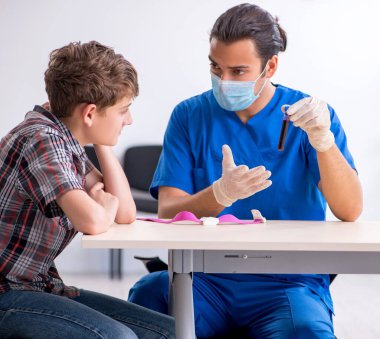 Genç çocuk hastanede doktoru ziyaret ediyor.