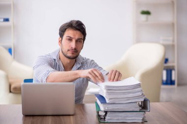 Young employee and too much work at workplace