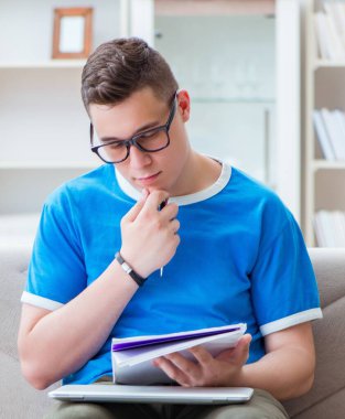 Sınavlara hazırlanan genç öğrenci evde bir kanepede ders çalışıyor.