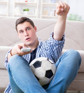 Evde futbol izleyen genç adam.