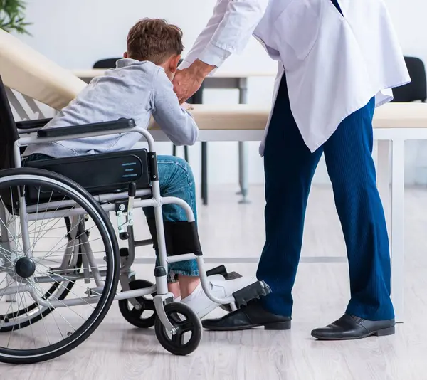 若い男性医師小児科医と車椅子の少年 — ストック写真