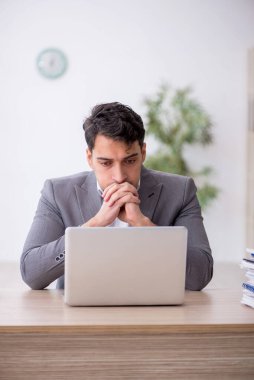 Young employee and too much work at workplace