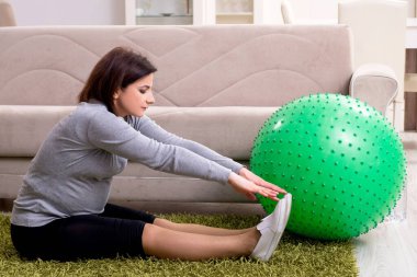 Yaşlı hamile kadın evde egzersiz yapıyor.