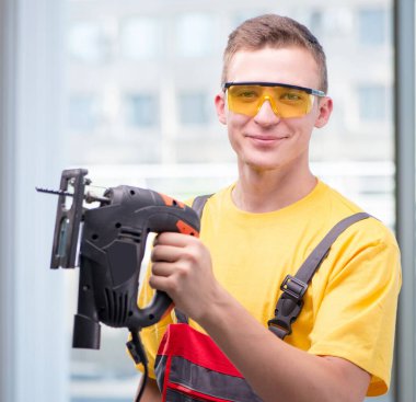 Sarı tulumlu genç inşaat işçisi.