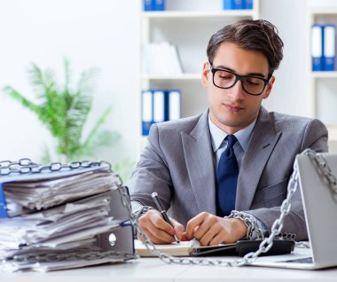 Ofis masasına zincirlenmiş meşgul bir çalışan.