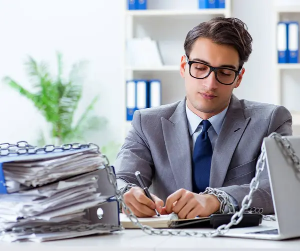 Ofis masasına zincirlenmiş meşgul bir çalışan.