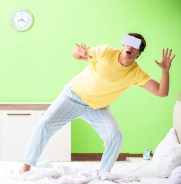 Yatak odasında sanal gözlüklü genç adam.