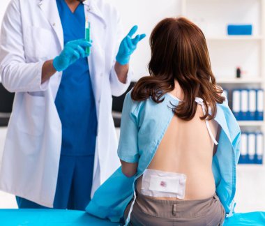 Yaralı genç kadın erkek doktoru ziyaret ediyor.