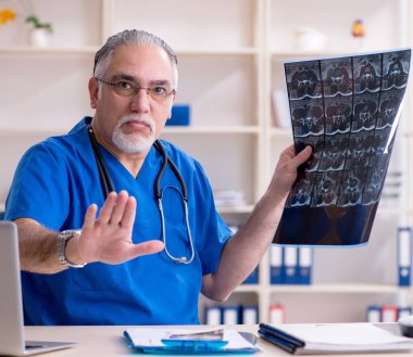 The white bearded old doctor radiologist working in clinic