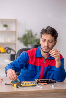 Laboratuvarda bilgisayar tamir eden genç bir tamirci.