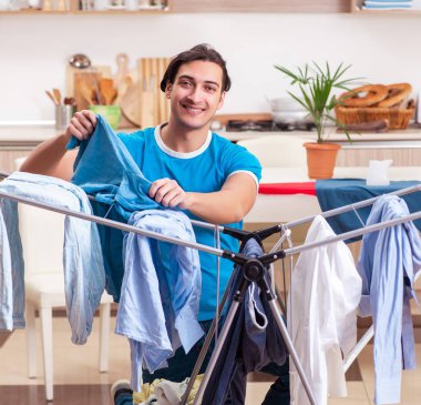 Genç adam evde ütü yapıyor.