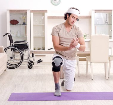 Evde egzersiz yapan yaralı genç adam.