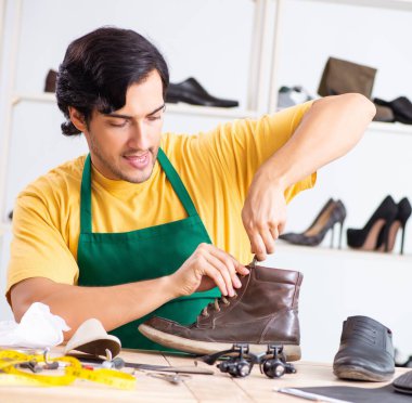 Atölyede ayakkabı tamir eden genç adam.