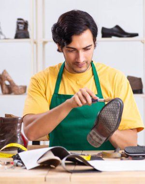 Atölyede ayakkabı tamir eden genç adam.