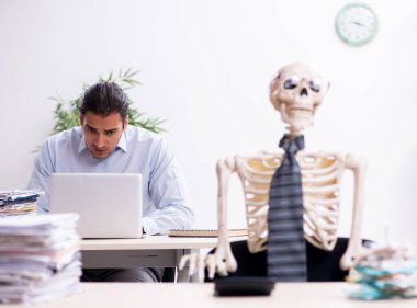 Ofisteki genç çalışan ve iskelet.