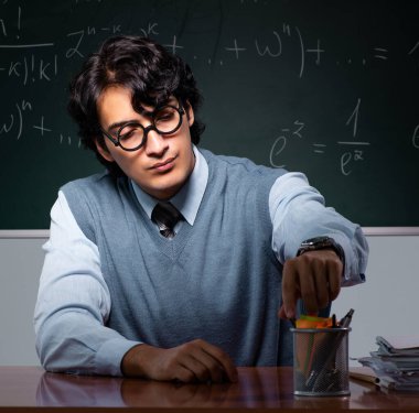 Tahtanın önündeki genç matematik öğretmeni.