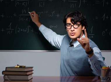 Tahtanın önündeki genç matematik öğretmeni.