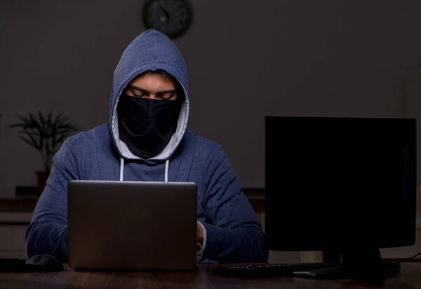 Male hacker hacking security firewall late in the office