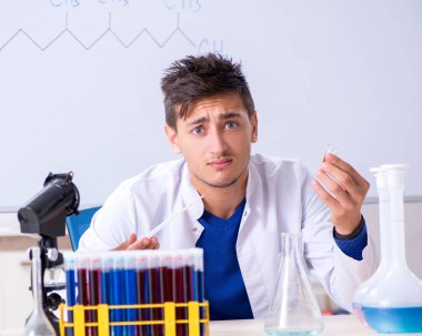 Laboratuvarda oturan genç kimyager.