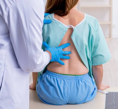 Genç yaralı kadın erkek doktor kayropraktik uzmanını ziyaret ediyor.