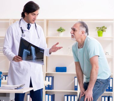 Yaşlı adam genç erkek doktoru ziyaret ediyor.