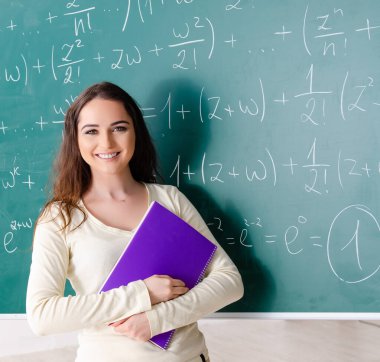 Tahtanın önündeki genç bayan matematik öğretmeni.
