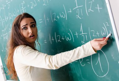 Tahtanın önündeki genç bayan matematik öğretmeni.