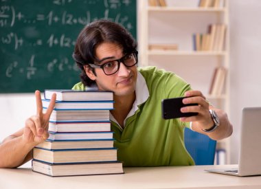 Tahtanın önünde formüllü yakışıklı öğrenci.