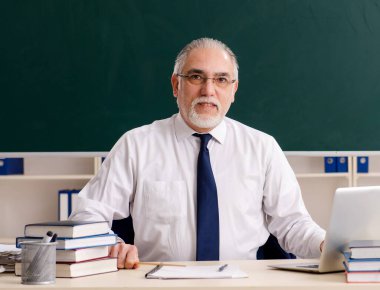 Tahtanın önündeki yaşlı erkek öğretmen.