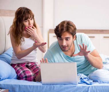 Yatak odasında dizüstü bilgisayarı olan genç çift.